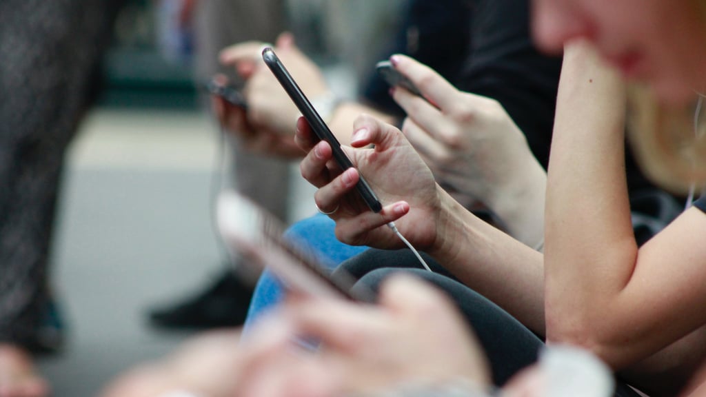 many hands holding on to mobile phones