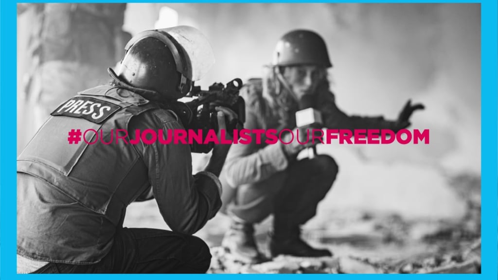 Image of female journalist crouching down while reporting in a hostile environment. This is a stock image and does not depict actual events