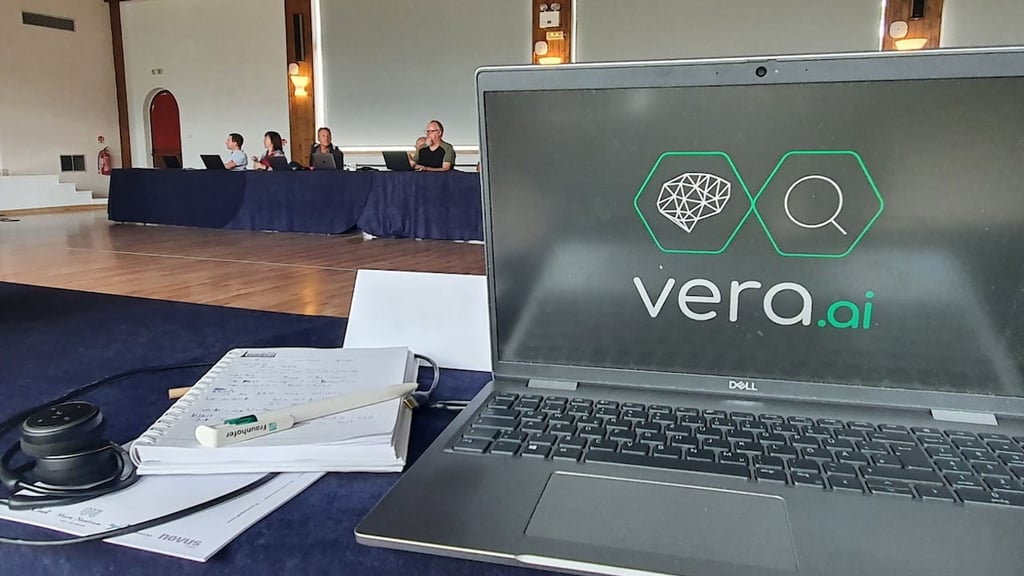 Foto showing a laptop with the vera.ai logo, on a desk in a conference setting