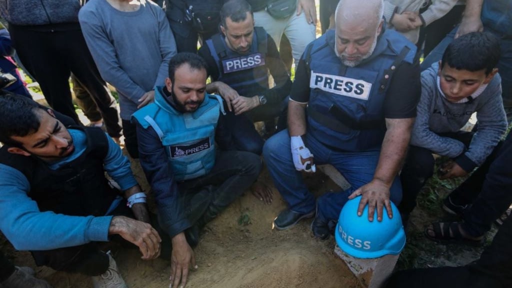 Image of journalists kneeling in mourning in Gaza