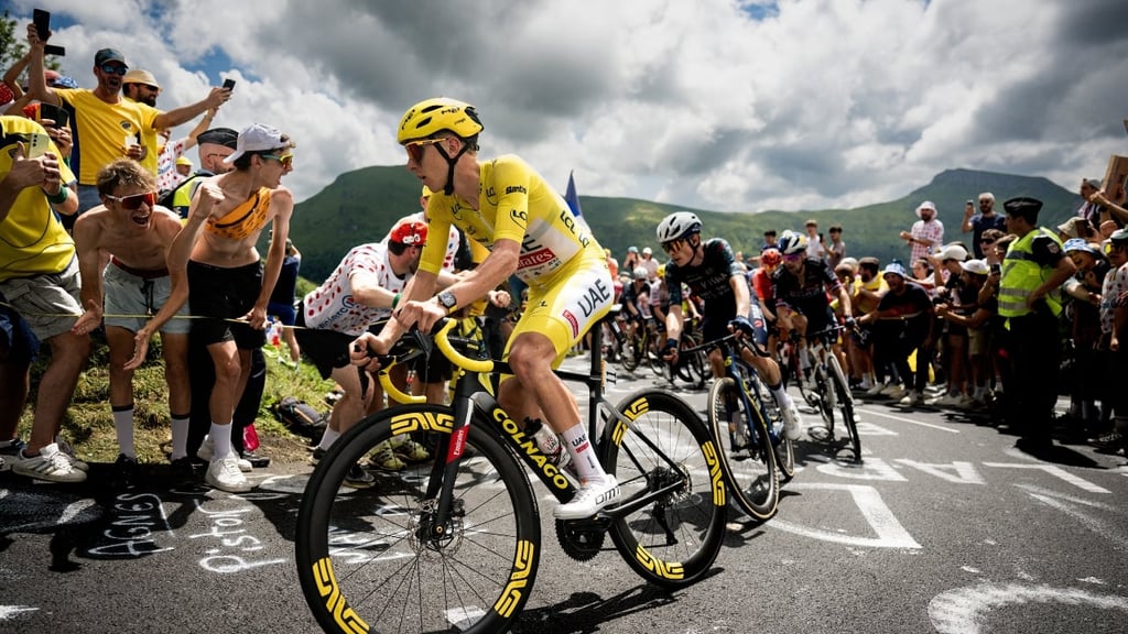 This is a photography of a cyclist during a race passing the supporting crowds at the side of the road